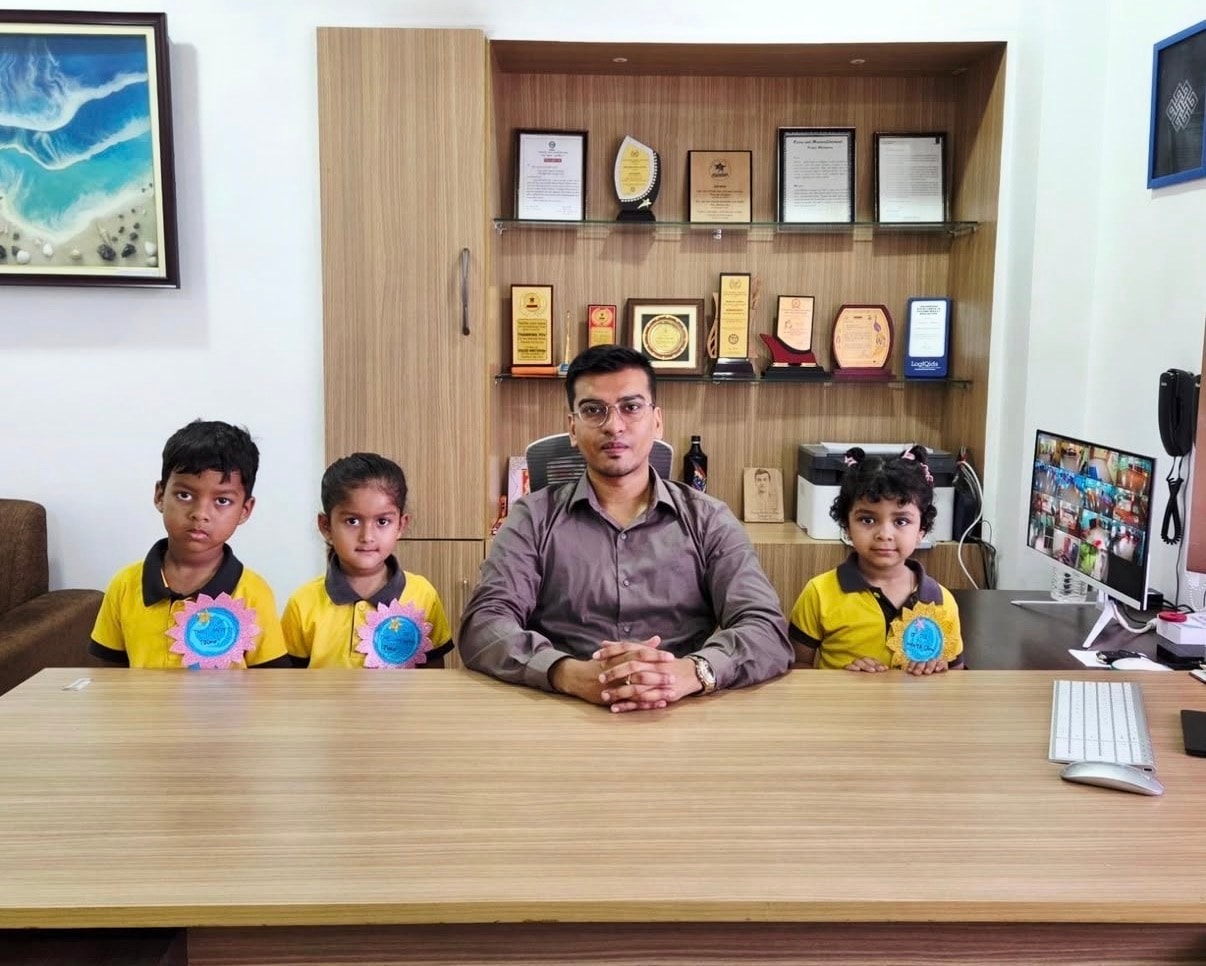 Centre Head Mr. Manash Sarma with three students wearing badges in his office