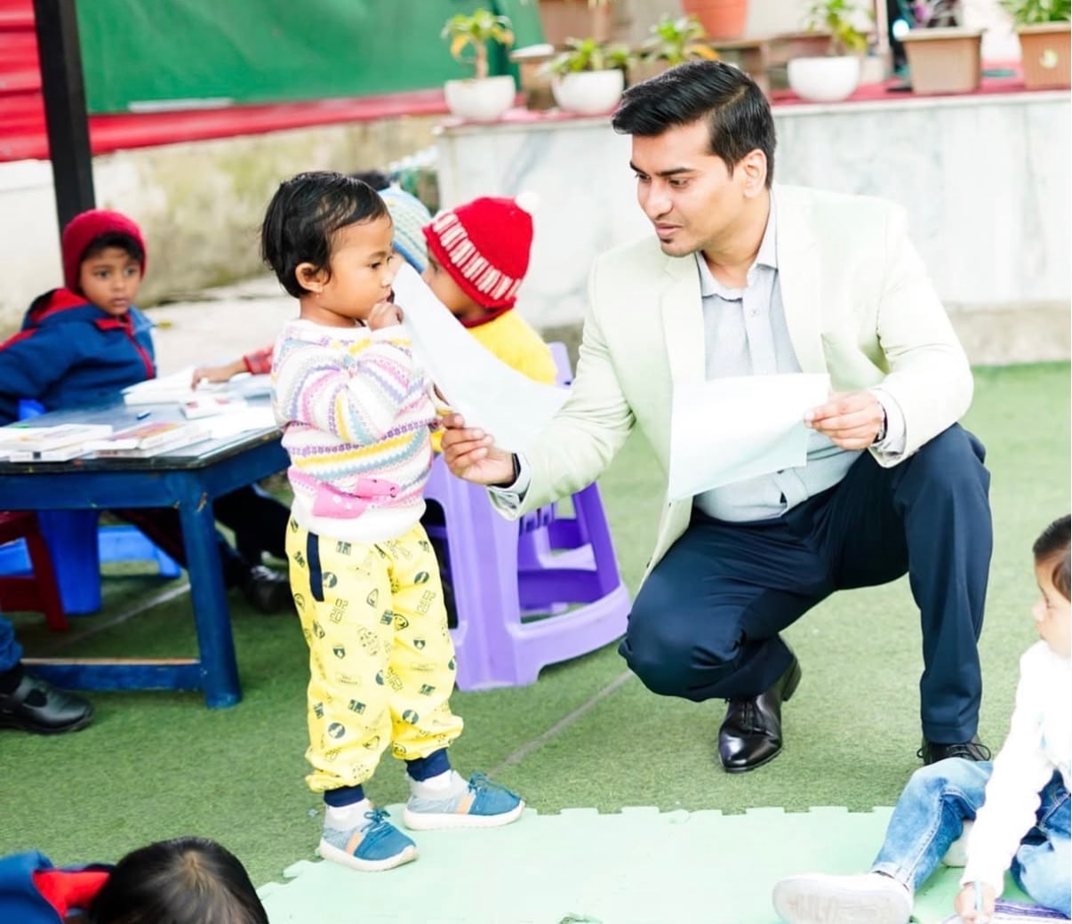 Centre Head crouching down to interact with a toddler in the outdoor play area